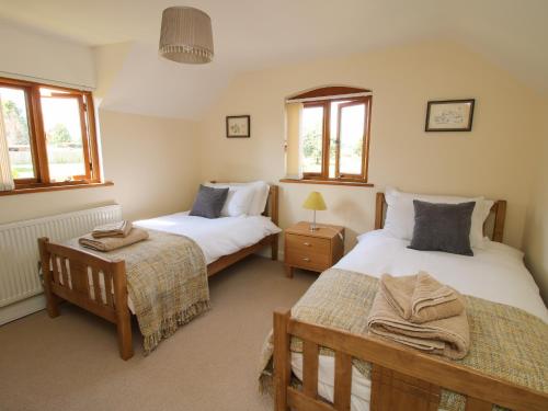 1 dormitorio con 2 camas y 2 ventanas en Ellenhall Farm Cottage en Stafford