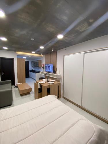 1 dormitorio con 1 cama blanca grande y cocina en Studio a pasos del shopping, en Asunción