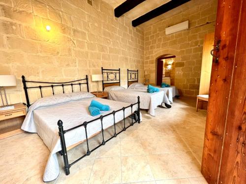 1 Schlafzimmer mit 3 Betten in einer Steinwand in der Unterkunft Birbuba House 2 in Għarb