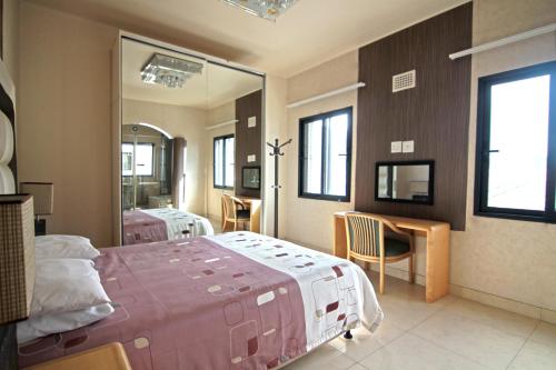 1 dormitorio con cama, escritorio y espejo en Qamaras, en Ciudad del Cabo