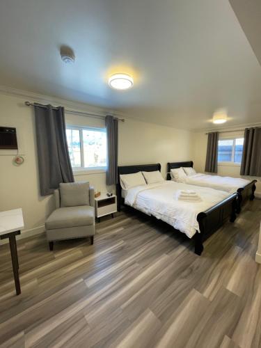 a bedroom with two beds and a chair at Destination INN in Radium Hot Springs