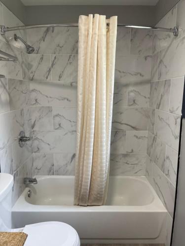 Baño blanco con bañera y cortina de ducha en Golden Hill Inn-Danbury, en Danbury
