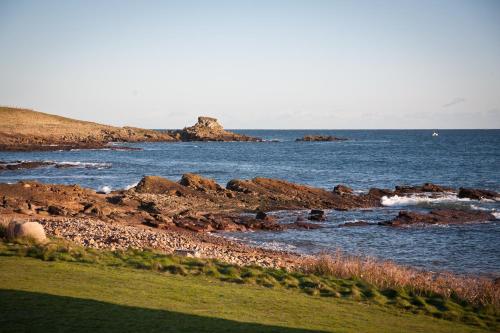 a view of a body of water with rocks and the ocean at Beach House Walk - Crail - Home from Home in Crail