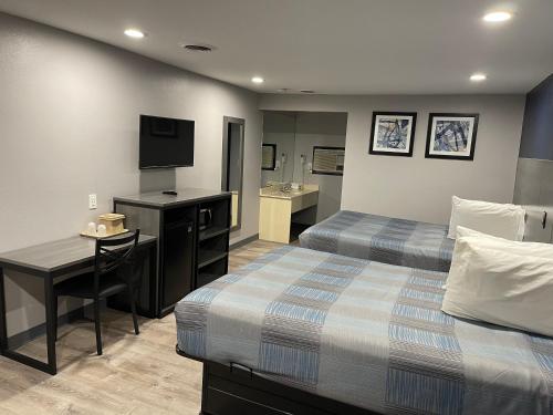 a hotel room with two beds and a desk and a television at Golden Hill Inn-Danbury in Danbury