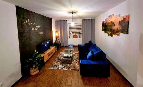 een woonkamer met een blauwe bank en een tv bij Apartament 'U PODNÓŻA GROMADZYNIA' in Ustrzyki Dolne