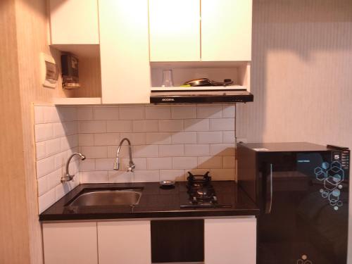 a small kitchen with a sink and a stove at Grand Kamala Lagoon By Mitra Propertindo in Bekasi