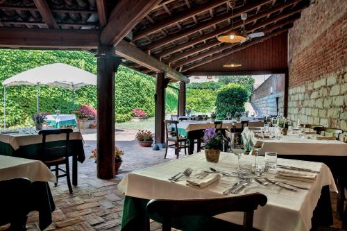 un restaurante con mesas y sillas blancas y un patio en Locanda della Rocca di Camagna en Camagna Monferrato