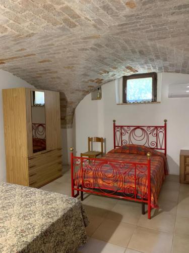 Una cama roja en una habitación con techo de piedra. en Casa di campagna Villa De Luca, en Bellante