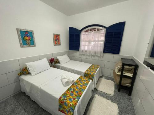 a room with two beds and a table and a window at Pouso da Meire in Tiradentes
