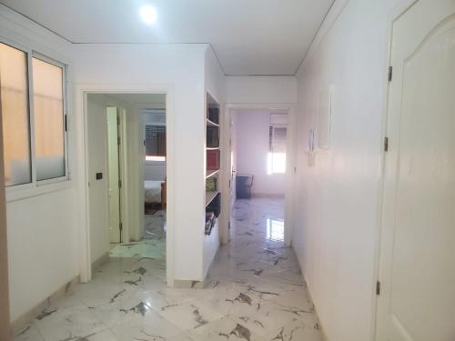 un pasillo con paredes blancas y suelo de mármol en My house 3 en Nador