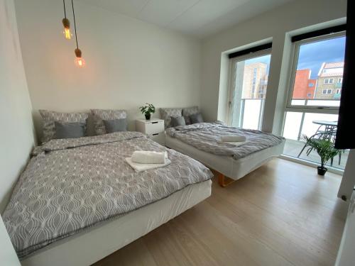 a bedroom with two beds and a large window at Central Apartment with Panorama Rooftop & Free Parking in Aarhus