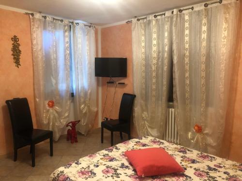 a bedroom with a bed and two chairs and curtains at B&B San Giorgio in Traversetolo