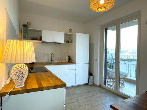 a kitchen with white cabinets and a table with a lamp at Casa Cannoni - Delizioso Appartamento Fronte Mare vista Stretto di Messina in Messina