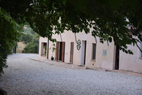 a white building with some doors and a street at Casale di Maro in Monte Giberto