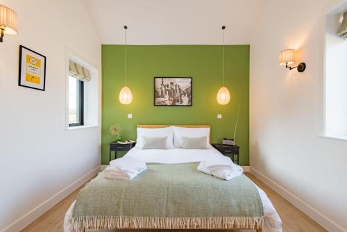 1 dormitorio con 1 cama grande y pared verde en Lacton Manor Barns by Bloom Stays, en Ashford