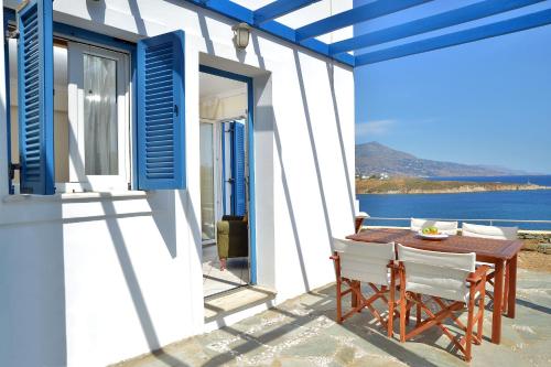 un patio con tavolo, sedie e vista sull'acqua di Andros Homes Sea Side Apartment & Studio a Gavrio