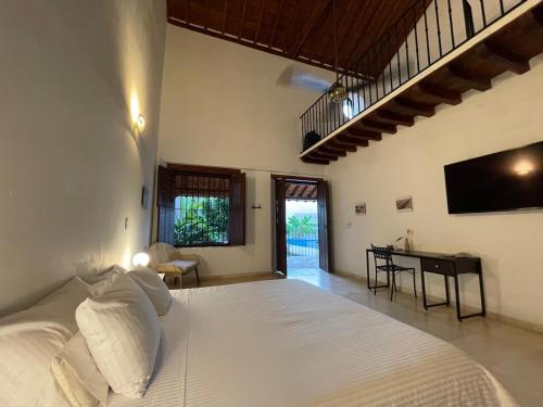 a bedroom with a large white bed and a desk at Karakali Boutique Hotel in Mompos