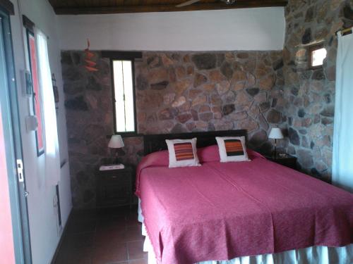 1 dormitorio con 1 cama con pared de piedra en Kailash Posada en San Marcos Sierras