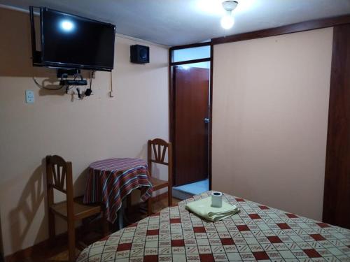 una camera con tavolo e TV a parete di Hostal Turístico El Cajamarquez a Lima