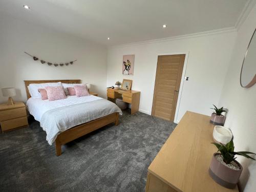 Un dormitorio con una cama con almohadas rosas y una mesa. en Beachfront Penthouse, Largs en Largs