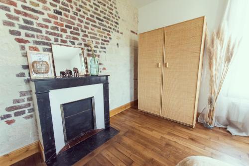 a living room with a fireplace and a brick wall at Domaine du lion rouge Piscine et Spa in Coucy-le-Château-Auffrique