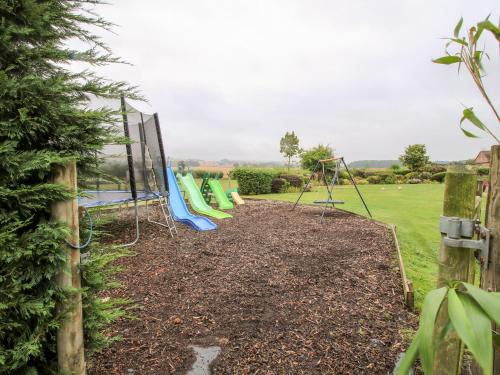 a playground with a bunch of swings in a yard at 6 Old Orchard in Much Wenlock