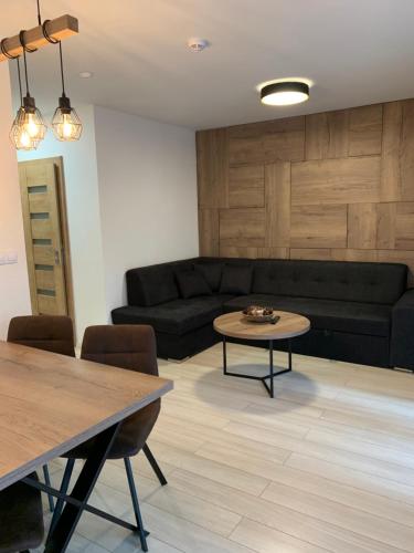 a living room with a black couch and a table at Apartmány Valča in Valča