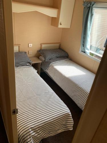 two beds in a small room with a window at 1 Martello Beach 8 berth holiday home with pools in Clacton-on-Sea