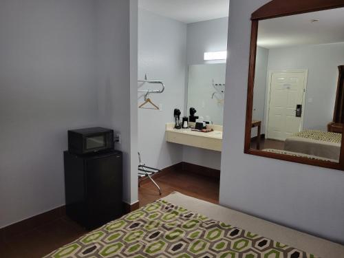 1 dormitorio con espejo, 1 cama y lavamanos en Scottish Inn & Suites, en Hankamer