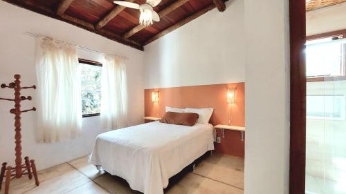 1 dormitorio con cama blanca y ventana en Casa Canto dos Saíras, en Paraty