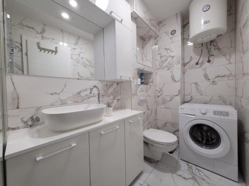 ein weißes Badezimmer mit einem Waschbecken und einer Waschmaschine in der Unterkunft Stan m&s, Boulevard-centar grada in Banja Luka