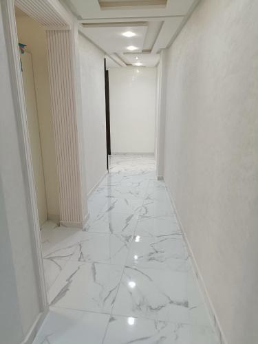an empty hallway with white marble floors and walls at Nador hay al Matar in Nador