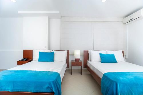 two beds in a room with blue and white at Hotel Sol de Piedemonte in Yopal