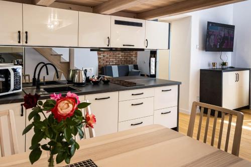 a kitchen with white cabinets and a table with a vase of roses at Old Cracow Apartment in Krakow