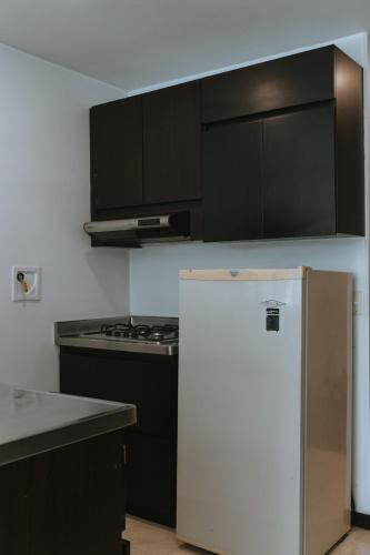 a kitchen with black cabinets and a white refrigerator at Travelers Orange Suites in Medellín