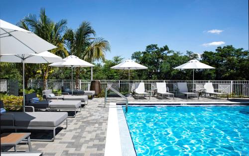 a swimming pool with lounge chairs and umbrellas at EVEN Hotel Miami - Airport by IHG in Miami