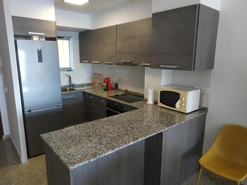 a kitchen with a counter with a microwave and a refrigerator at Ca Vicent in Calpe