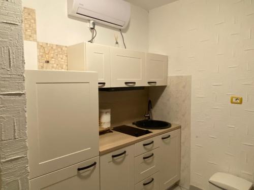 una cocina con armarios blancos y fregadero en Farfalle di Valle, en Bale