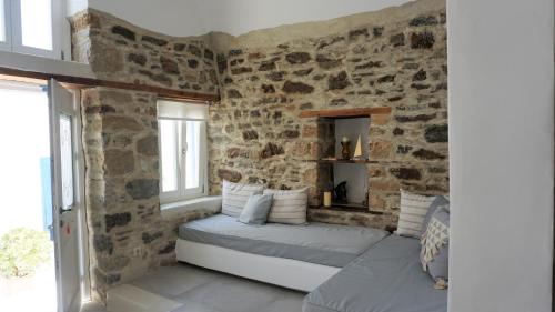 a room with a stone wall with couches and windows at Traditional Holiday Home in Astypalaia Town