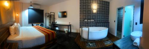 グアダラハラにあるHangar Inn Select Aeropuerto Guadalajaraのベッドルーム(バスタブ、ベッド1台付)、バスルームが備わります。