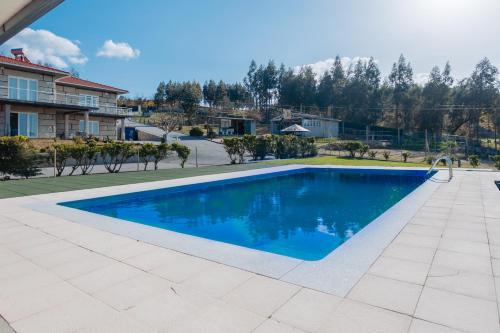 a swimming pool with blue water in a yard at Sorte do Castelo in Marco de Canaveses