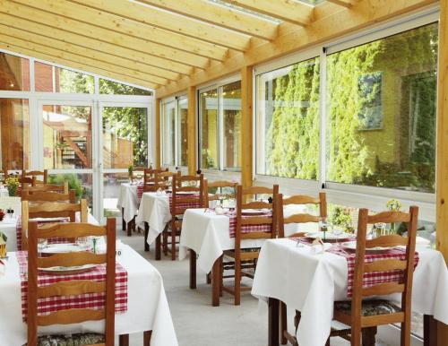 un restaurant avec des tables et des chaises blanches et des fenêtres dans l'établissement Logis Hôtel Restaurant De La Poste et SPA de Montagne, à Le Bonhomme