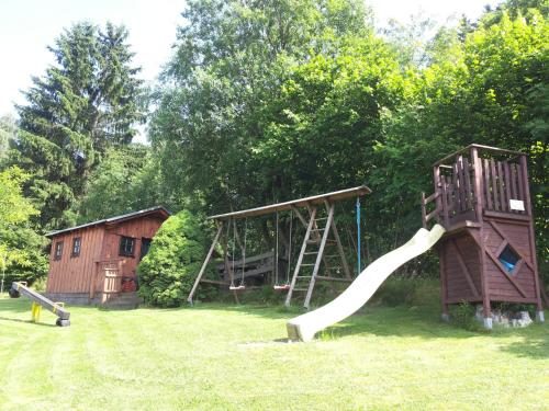 a playground with a slide in a yard at Pension "Dorfkrug" in Winterberg