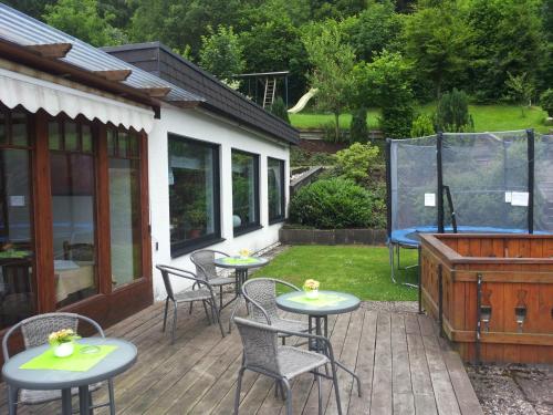 a patio with tables and chairs on a deck at Pension "Dorfkrug" in Winterberg