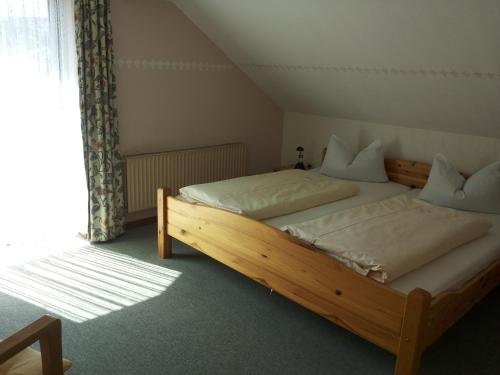 a bedroom with a wooden bed with white pillows at Pension "Dorfkrug" in Winterberg