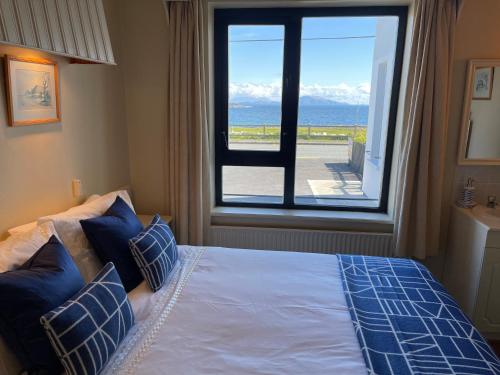 a bedroom with a bed with a view of the ocean at Teach Cruachan Large-Group Holiday Home in Dooagh