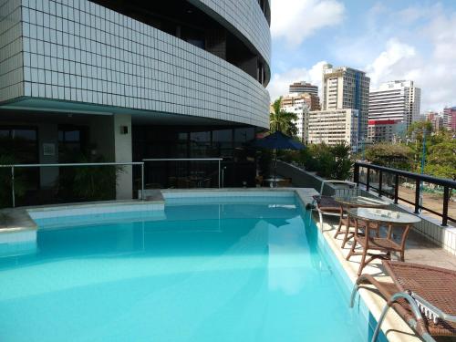 uma piscina com cadeiras e um edifício em Flat particular no Blue Tree Fortaleza em Fortaleza