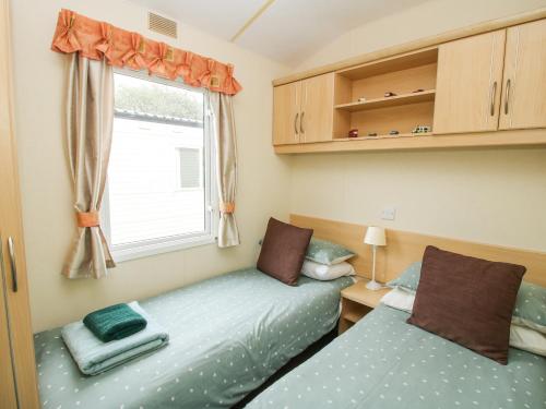 2 Betten in einem kleinen Zimmer mit Fenster in der Unterkunft 4 Old Orchard in Much Wenlock