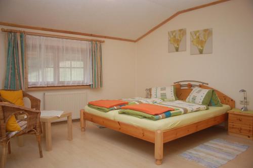 1 dormitorio con 1 cama, 1 silla y 1 ventana en Ferienwohnung Hofer, en Pruggern
