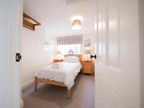 a small bedroom with a bed and a window at Padstow Escapes - Captains Cottage in Padstow